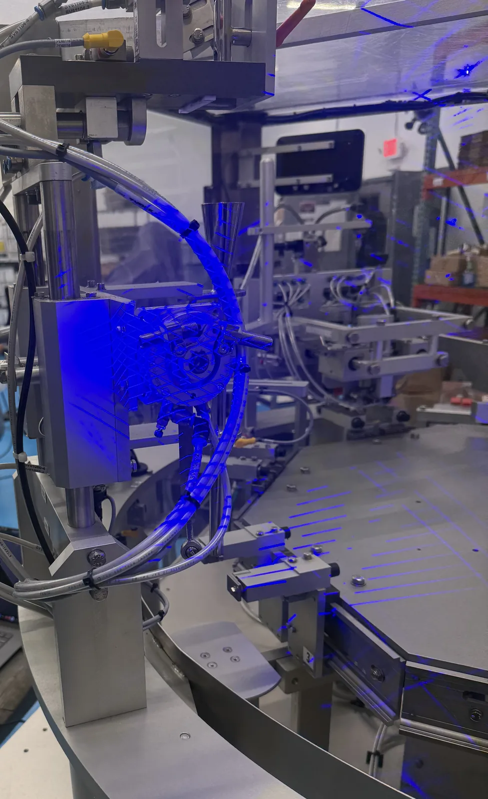 Blue structured-light 3D scanner projecting onto a rotary indexing head on a production line during an on-site scan