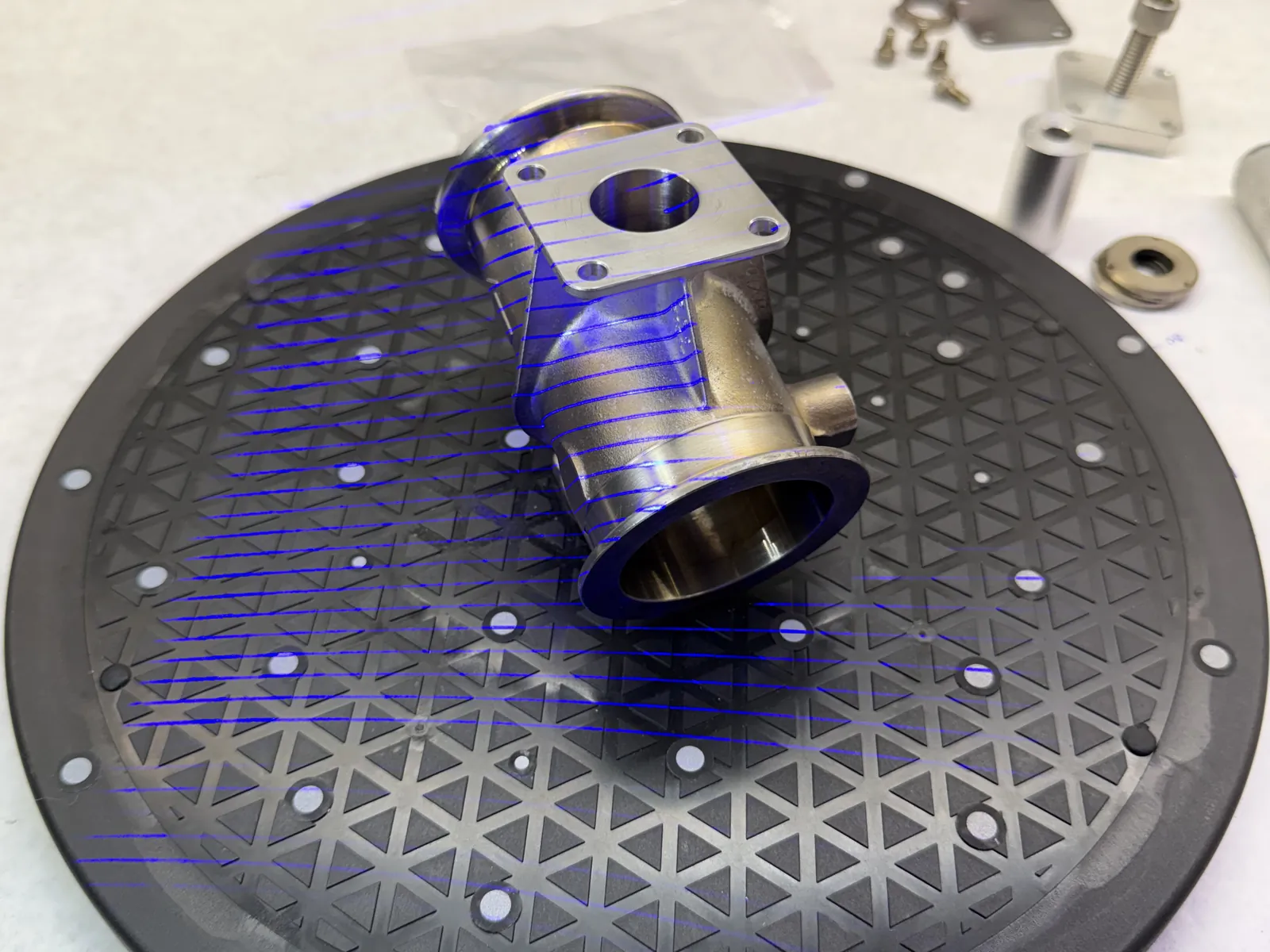 Stainless steel sanitary valve body with tri-clamp flanges on a 3D scanning turntable, blue laser lines tracing its surface